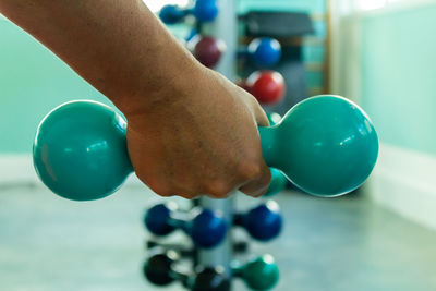 Cropped hand of man holding dumbbell in gym