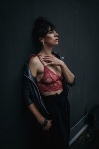 Young woman standing against wall