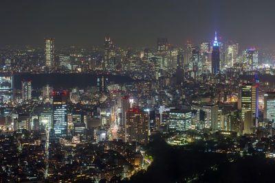 Illuminated cityscape against sky at night