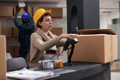 Portrait of young woman using mobile phone while standing in office