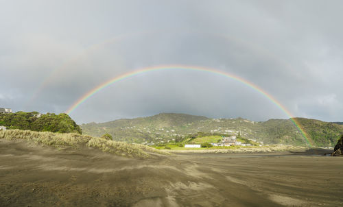 Scenic view of rainbow over land against sky