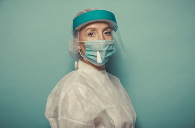 Portrait of doctor wearing mask against blue background