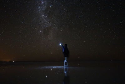 Rear view of woman standing against sky at night