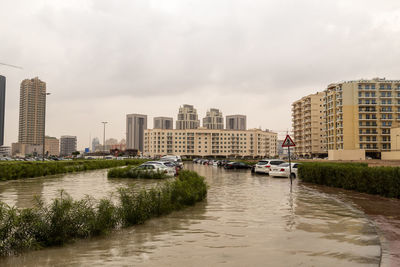 River amidst buildings in city against sky