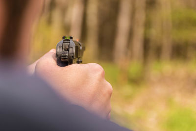 Cropped hand of man aiming with gun