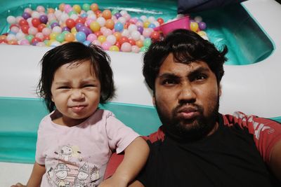 High angle portrait of father with daughter lying on wading pool