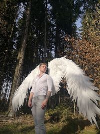 Low angle view of man wearing costume wings while standing against trees