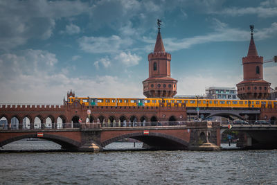 Arch bridge over river against cloudy sky