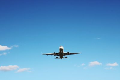 Low angle view of airplane flying against blue sky