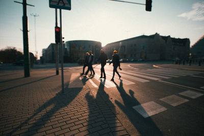 People crossing road in city against sky