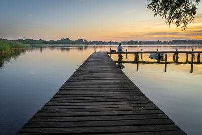 Pier over lake against sky during sunset