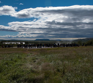 Scenic view of grassy field against cloudy sky