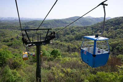 Overhead cable car on landscape against sky