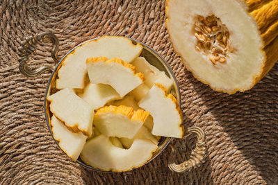 Melon slices in a traditional plate and half a juicy melon on thatched deck, top view,