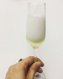 Close-up of hand holding wineglass against white background