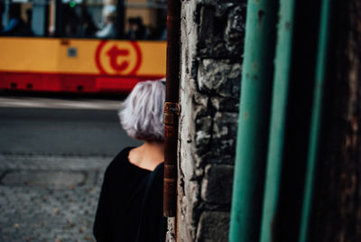 Rear view of woman standing by wall