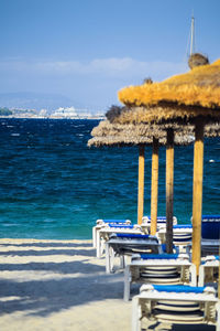 Close-up of deck chairs on beach against blue sky