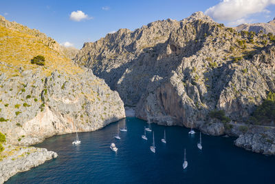 Scenic view of sea by mountain against sky