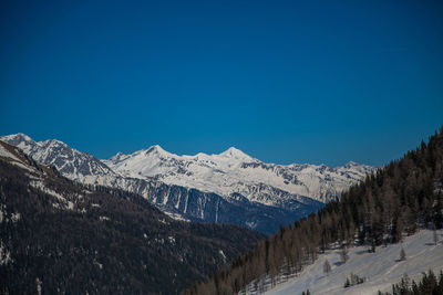 Scenic view of snowcapped mountains against clear blue sky