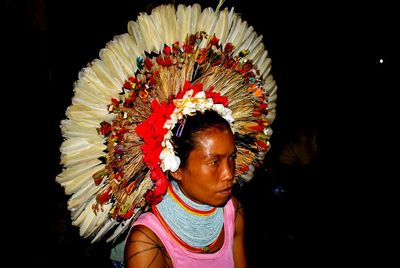 Woman wearing headdress against black background