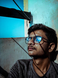 Portrait of man wearing eyeglasses against wall