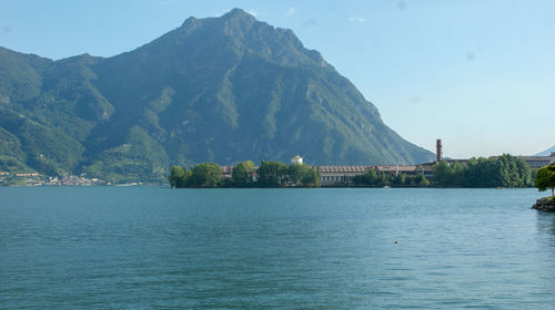 Scenic view of sea by mountain against sky