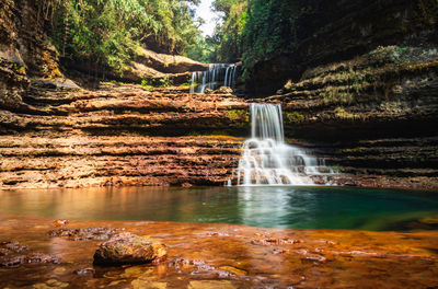 Waterfall streams falling from mountain with blurred water surface at morning from low angle