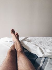 Low section of man relaxing on bed at home