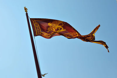 Low angle view of flags against clear blue sky