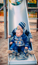 Cute sibling sitting on slide at playground