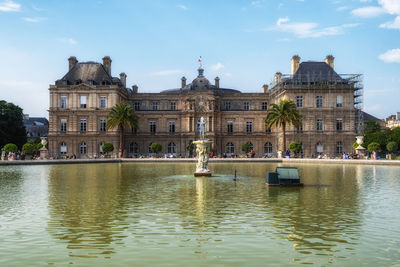 Buildings by river against sky