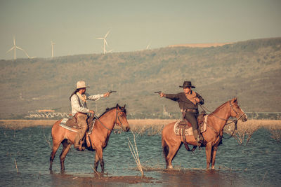 People riding horse cart on land against sky