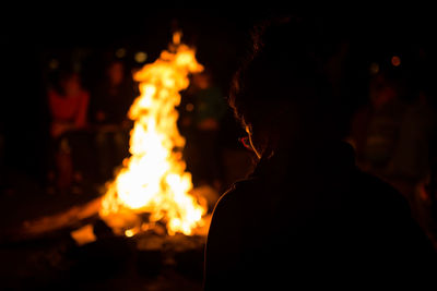 Rear view of woman sitting by bonfire at night