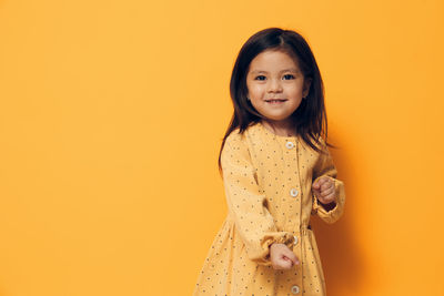 Portrait of young woman standing against yellow background