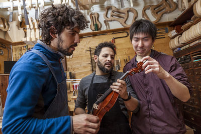 Male workers examining violin in workshop