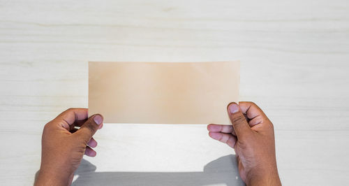 Close-up of hand holding book against white background