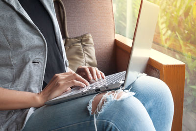 Midsection of man holding mobile phone while sitting on seat