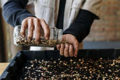 Man removing seeds from glass jar at workshop