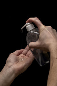 Midsection of man holding bottle against black background