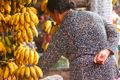 Rear view of woman standing by bananas at market