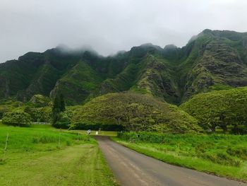 Road amidst green landscape against sky