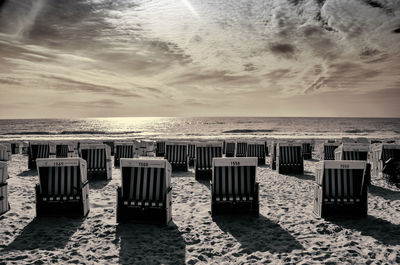 Chairs on beach against sky during sunset