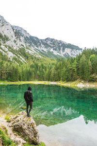 Rear view of man standing in lake against mountains