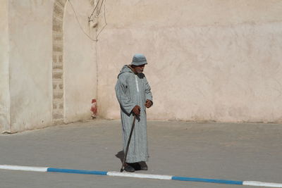 Man holding umbrella standing against wall