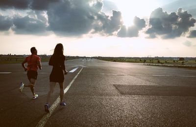 Rear view of people running on road against sky