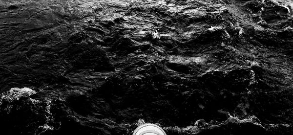 Low section of person standing on rock by sea