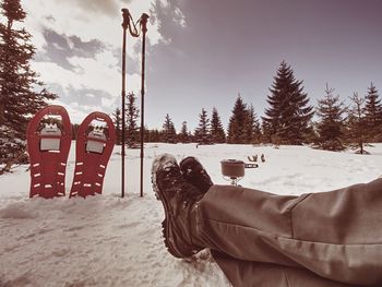 Red snowshoes and trekking poles ready in snow, vacation in mountains, trail in snowy landscape.