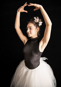 Portrait of a smiling young woman standing against black background