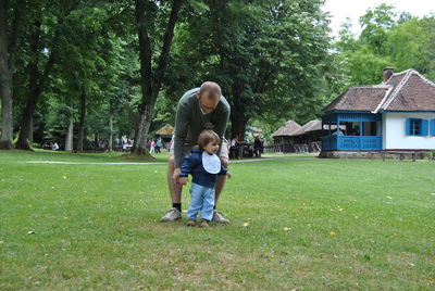 Father assisting son in walking on field