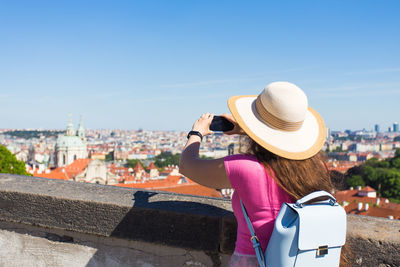 Rear view of woman looking at cityscape against sky